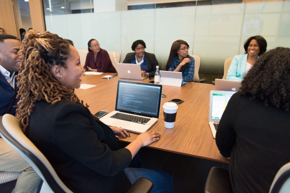 Colleagues around a conference table with laptops during a team meeting