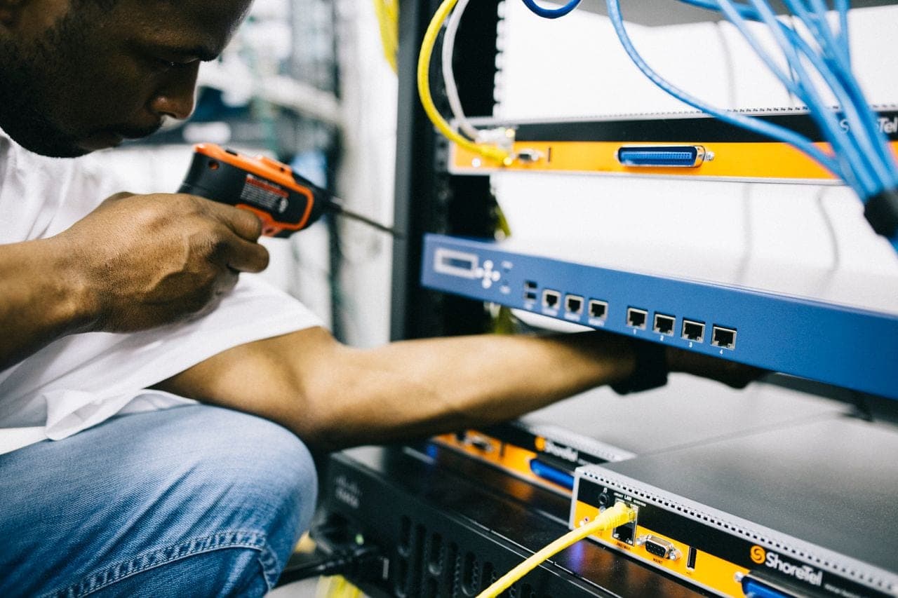 A technician plugs a cable into a network switch
