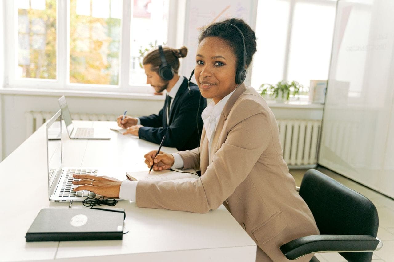 Customer support agents wearing headsets work at laptops