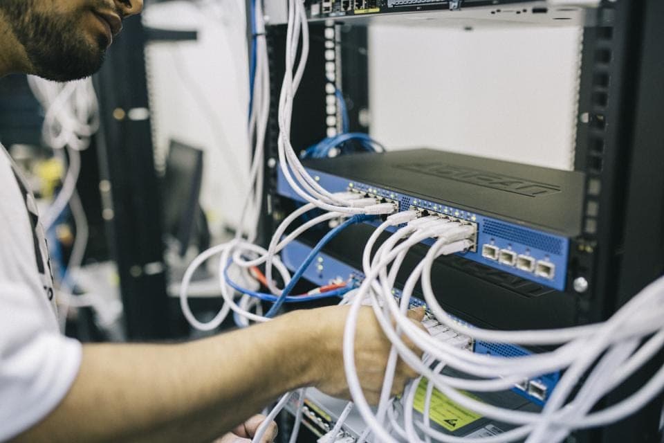 A technician connects network cables in a server rack